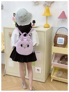 Child wearing a cute purple rabbit backpack with 3D ears in a cozy nursery room