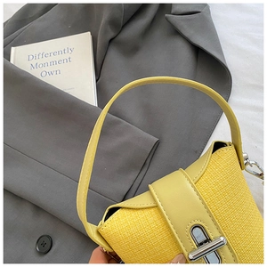 Detailed view of yellow straw and leather bucket bag with silver metal twist lock