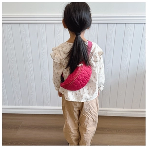 Vue détaillée d'un enfant portant un sac de poitrine rose fuchsia matelassé en cœur