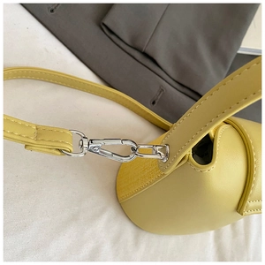 Detail of yellow shoulder bag featuring smooth leather and woven texture with silver hardware