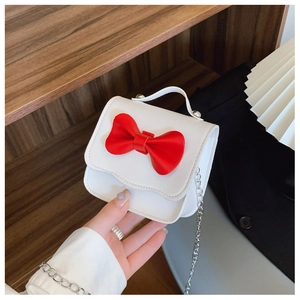 Detailed close-up of mini hand-held bag with red bow and elegant silver chain strap