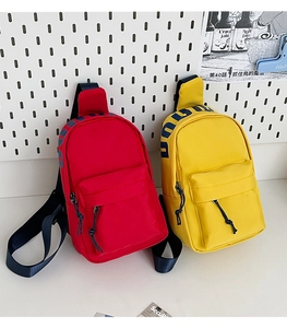 Close-up of red and yellow nylon crossbody bags with blue lettering on adjustable straps