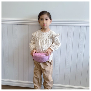 Sac banane rose matelassé cœur pour enfant porté par une fille en chemise fleurie