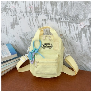 Detail of yellow nylon crossbody bag with purple chain and logo on wood table