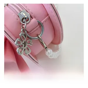 Detail of silver hardware hook and flower charm on pink leather girls' crossbody bag