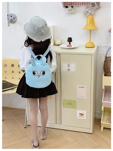 Light blue cartoon bunny backpack with 3D ears shown on a child in a cozy home setting