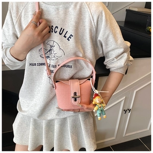 Pink woven bucket bag with silver twist lock and cute cartoon charm shown on model