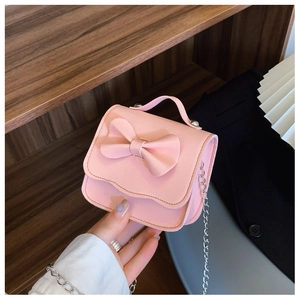 Close-up of pink mini crossbody bag with bow decoration and silver chain strap for girls