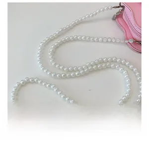 Detail of pink girls' purse with elegant pearl strap and sweet scalloped edges