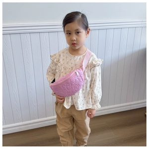 Détail d'un sac de poitrine rose pour enfant avec matelassage en cœur et sangle réglable