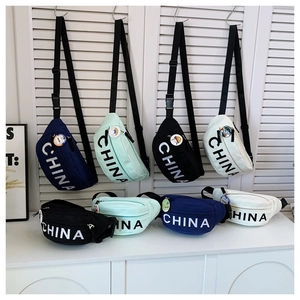 Dettaglio di borse da petto in tela colorata con logo CHINA e spille decorative a fumetti