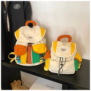 Detail view of large and small color-block canvas backpacks for children on display stand