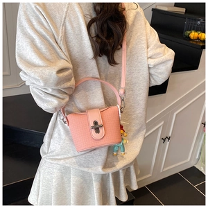 Detail of pink knit bucket bag with silver twist lock and cartoon charm pendant
