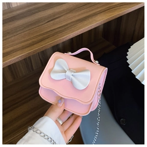 Detailed view of pink mini girl's bag with white bow and silver metal chain strap