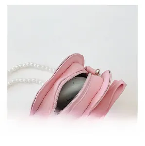 Detail view of the pink girl's bag interior with pearl strap and bow showing storage space