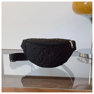 Détail de motifs de cœurs matelassés noirs sur un sac de poitrine avec sangle réglable