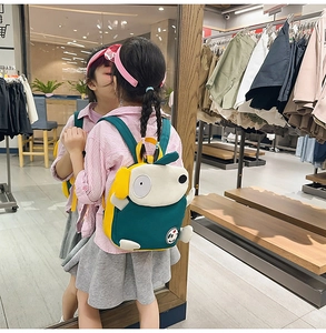 Detailansicht eines niedlichen grün-gelben Welpen-Rucksacks getragen von einem Kind