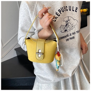 Detail of yellow woven bucket bag with silver twist lock and cute pearl charm
