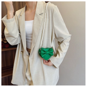 Detail of heart-shaped green girls purse with bow decoration and pearl shoulder strap