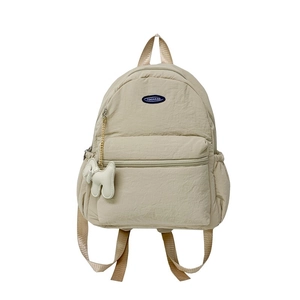 Minimalist beige nylon backpack for kids with a cute dog pendant on a white background