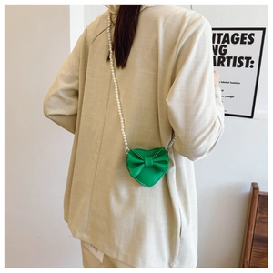 Detail of green heart-shaped girls crossbody bag with bow and pearl chain strap