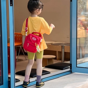 Kids red mini crossbody bag with adjustable strap shown on a young model in casual wear
