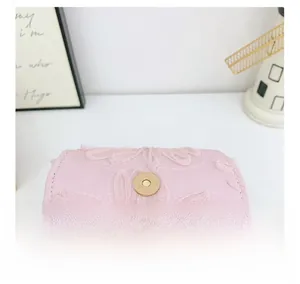 Close-up of pink lace fabric detail and gold magnetic snap closure on girls handbag