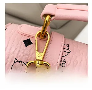 Close-up of pink leather backpack with golden metal hook and cartoon cat pattern details