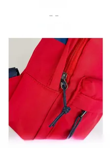 Detail of red crossbody bag showing smooth metal zipper with navy braided puller