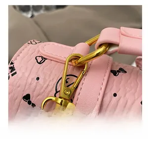 Détail du crochet doré brillant sur cuir rose grainé avec motif de nœud papillon
