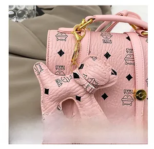 Close-up of pink textured leather bag with diamond patterns and cute dog charm detail