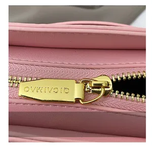 Détails macro d'une fermeture éclair dorée lisse sur un sac à bandoulière en cuir rose
