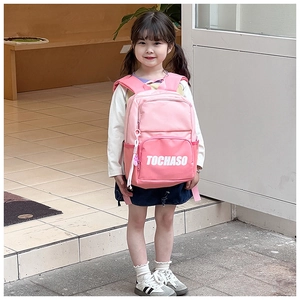 Pink children backpack with TOCHASO logo worn by a young girl in a bright setting