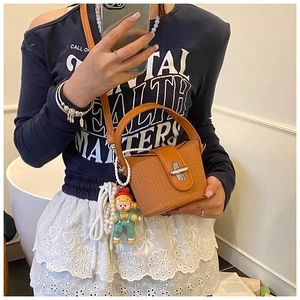 Detail of orange textured leather mini bucket bag with silver clasp and cute charm