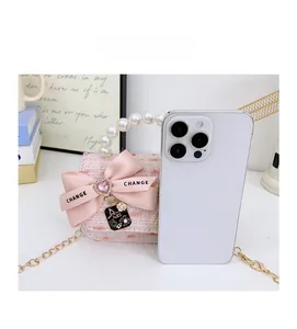 Size comparison of mini pink tweed pearl bag with bow and No 5 charm next to a phone