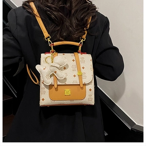 Mini backpack featuring orange straps and a white bear charm shown on a model's back