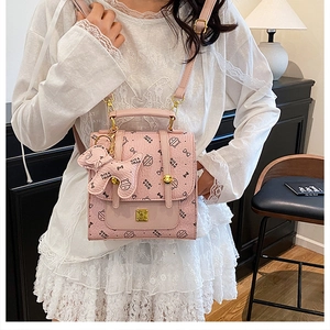 Détail du sac bandoulière rose à motif nœud, finitions dorées et breloque chien mignonne