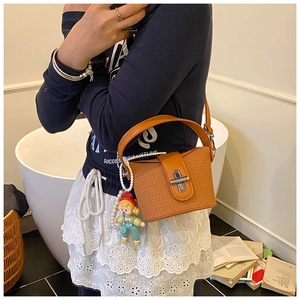 Detail of orange textured bucket bag with silver turn-lock and cute pearl charm