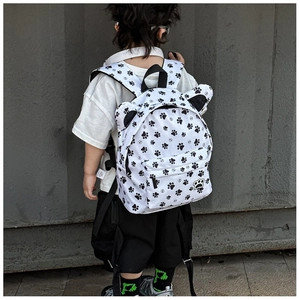 Detail view of cartoon kids backpack featuring cute ear decor and black footprint pattern