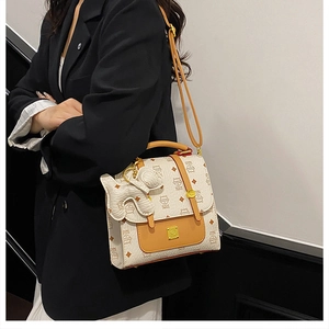 Detail of printed crossbody bag with dog charm and contrast flap on female model