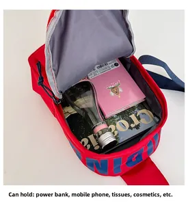 Detail view of red nylon crossbody bag interior showing spacious storage and blue lettering