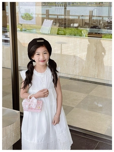 Girl in white embroidery dress holding a pink sequin handbag with pearl handle