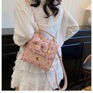 Détail du sac à dos rose style collège avec imprimés nœuds et pendentif chiot