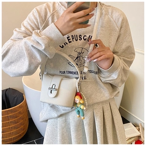 Detail of off-white textured crossbody bucket bag with silver lock and pearl doll pendant