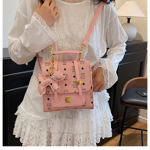 Detailed view of pink quilted handbag with gold lock and cute dog charm on a white dress
