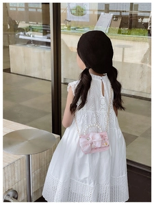 Pink tweed kids shoulder bag with pearl handle and mesh bow worn by a child model