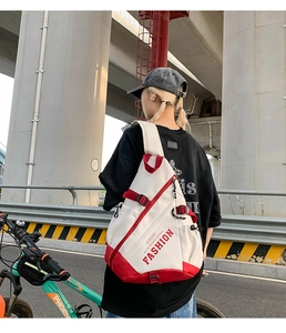 Detail of a white crossbody bag with FASHION lettering worn during outdoor cycling