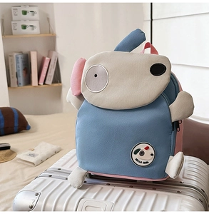 Detail eines süßen blau-rosa Hunde-Rucksacks auf einem weißen Koffer für Kinder