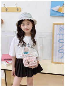 Pink tweed mini bag with pearl handle and bow shown worn by child model indoors