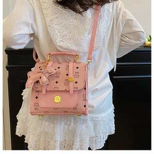Detail of light pink monogrammed handbag with Oica Mao print and dog charm accessory